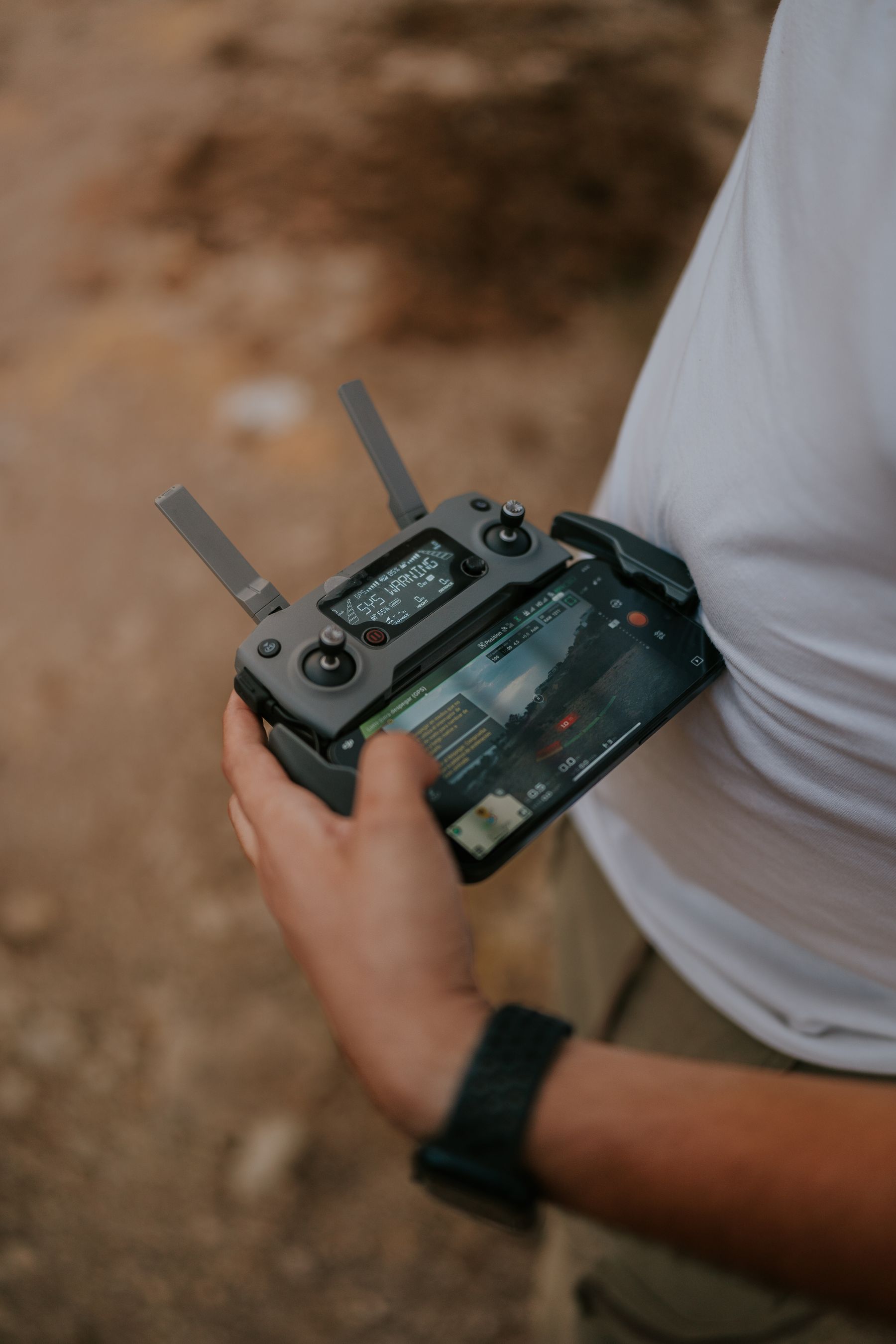 Illustrative close-up of a drone operator checking a controller outdoors.
